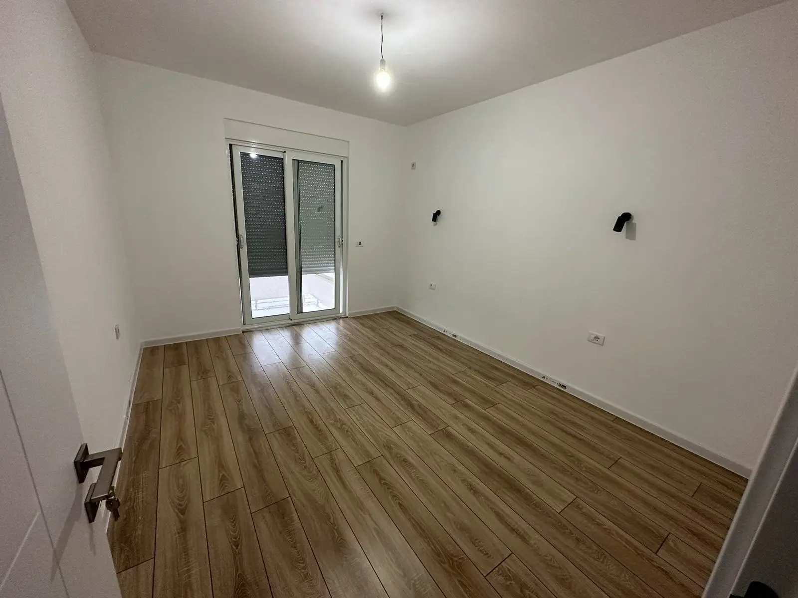 Modern Ulcinj Montenegro property: bright room, wood floors, glass door to outdoors. Featured on montenegro-listings.me by Ekosphere DOO.