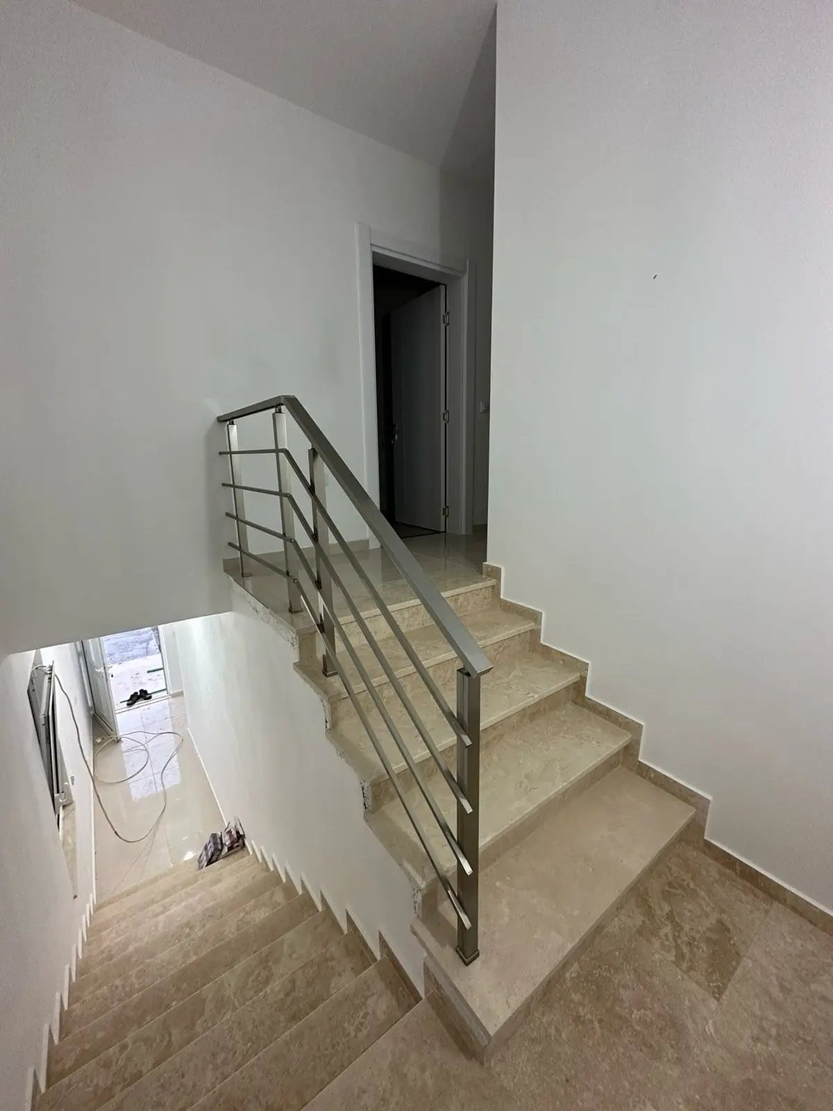 Modern staircase with beige steps, metal handrail, and bright white walls—ideal Ulcinj real estate by ekosphere doo. Invest today!.