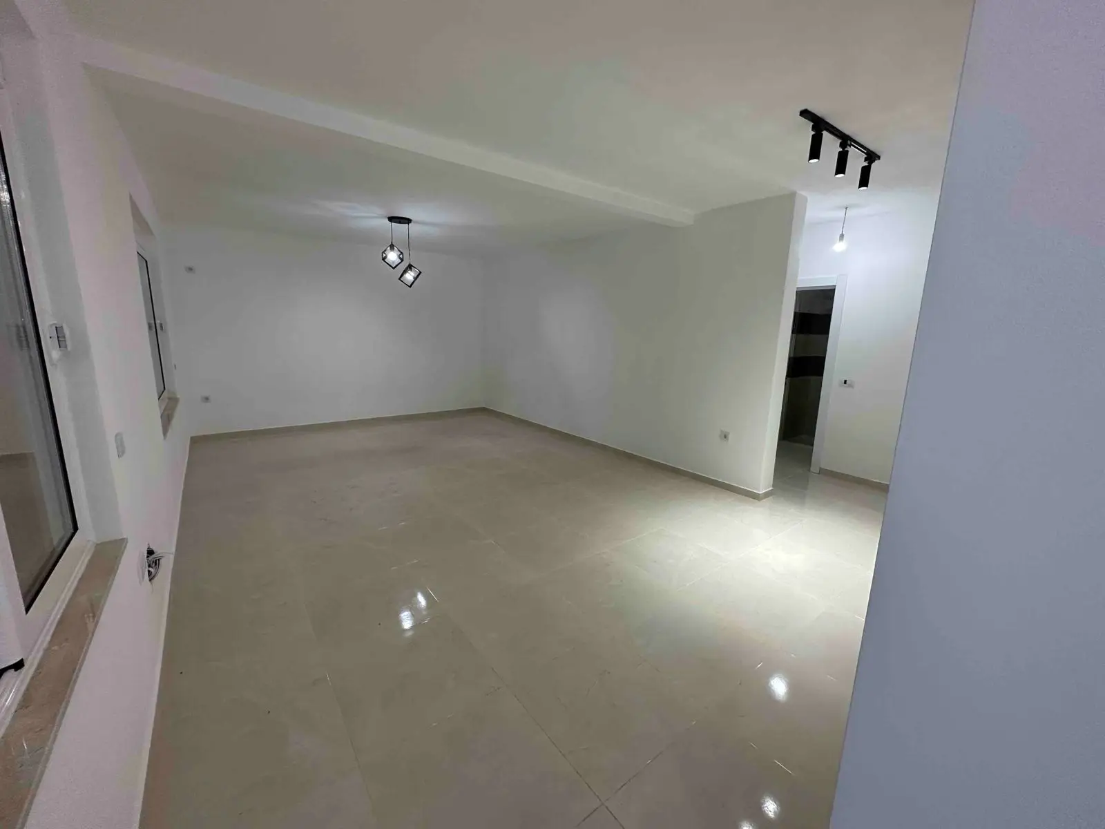 Modern, sunlit room with glossy beige tiles and white walls—prime Ulcinj property for sale on montenegro-listings.me by ekosphere doo.