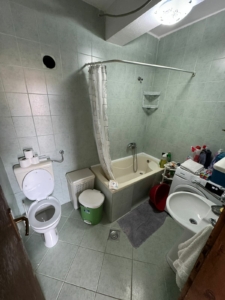 Modern Ulcinj bathroom with green tiles, tub, washer & amenities—ideal Montenegro investment. View at montenegro-listings.me by ekosphere doo.
