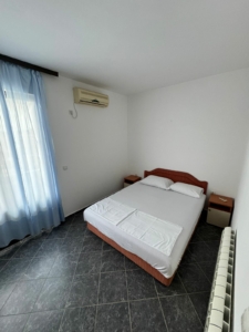 Modern Ulcinj Montenegro bedroom with double bed, AC, nightstands, blue curtains; exclusive real estate by montenegro-listings.me.