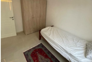 Modern, airy Ulcinj bedroom with white bed, wardrobe, and rug—ideal Montenegro property investment by Ekosphere on montenegro-listings.me.