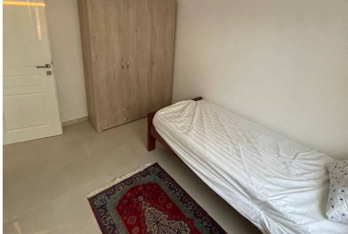 Modern, airy Ulcinj bedroom with white bed, wardrobe, and rug&mdash;ideal Montenegro property investment by Ekosphere on montenegro-listings.me.