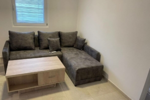 Modern Ekosphere home in Ulcinj: gray L-shaped sofa, wood coffee table, window blinds—exclusive at montenegro-listings.me by Ekosphere doo.