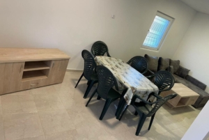 Modern Ulcinj property dining area with sleek table, six black chairs, sofa, and wood details—exclusive at montenegro-listings.me.