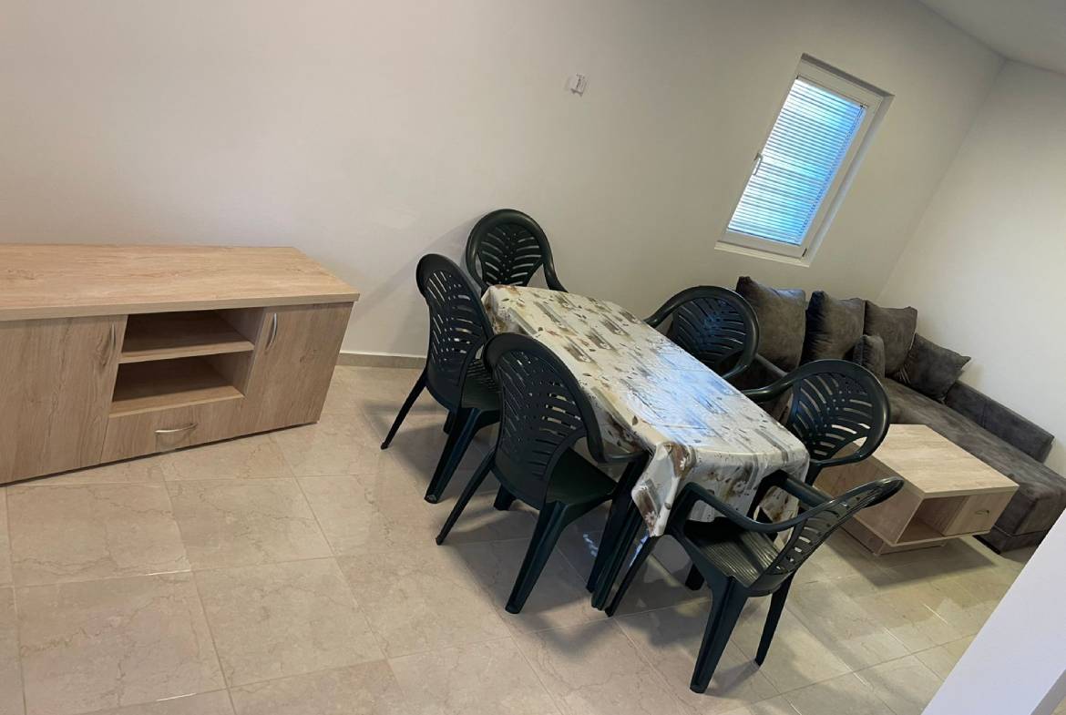 Modern Ulcinj property dining area with sleek table, six black chairs, sofa, and wood details&mdash;exclusive at montenegro-listings.me.