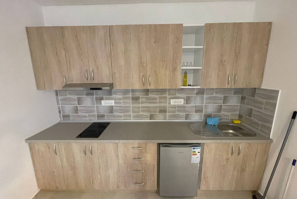 Modern Ulcinj kitchen with light wood cabinets, sleek backsplash, and cooktop&mdash;ideal property investment on montenegro-listings.me by ekosphere doo.