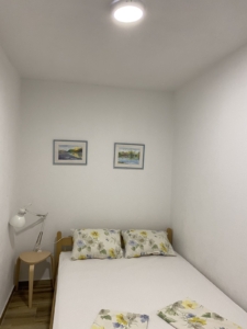 Charming Ulcinj bedroom for sale: single bed, floral pillows, stylish wood floors—ideal property on montenegro-listings.me by ekosphere doo.