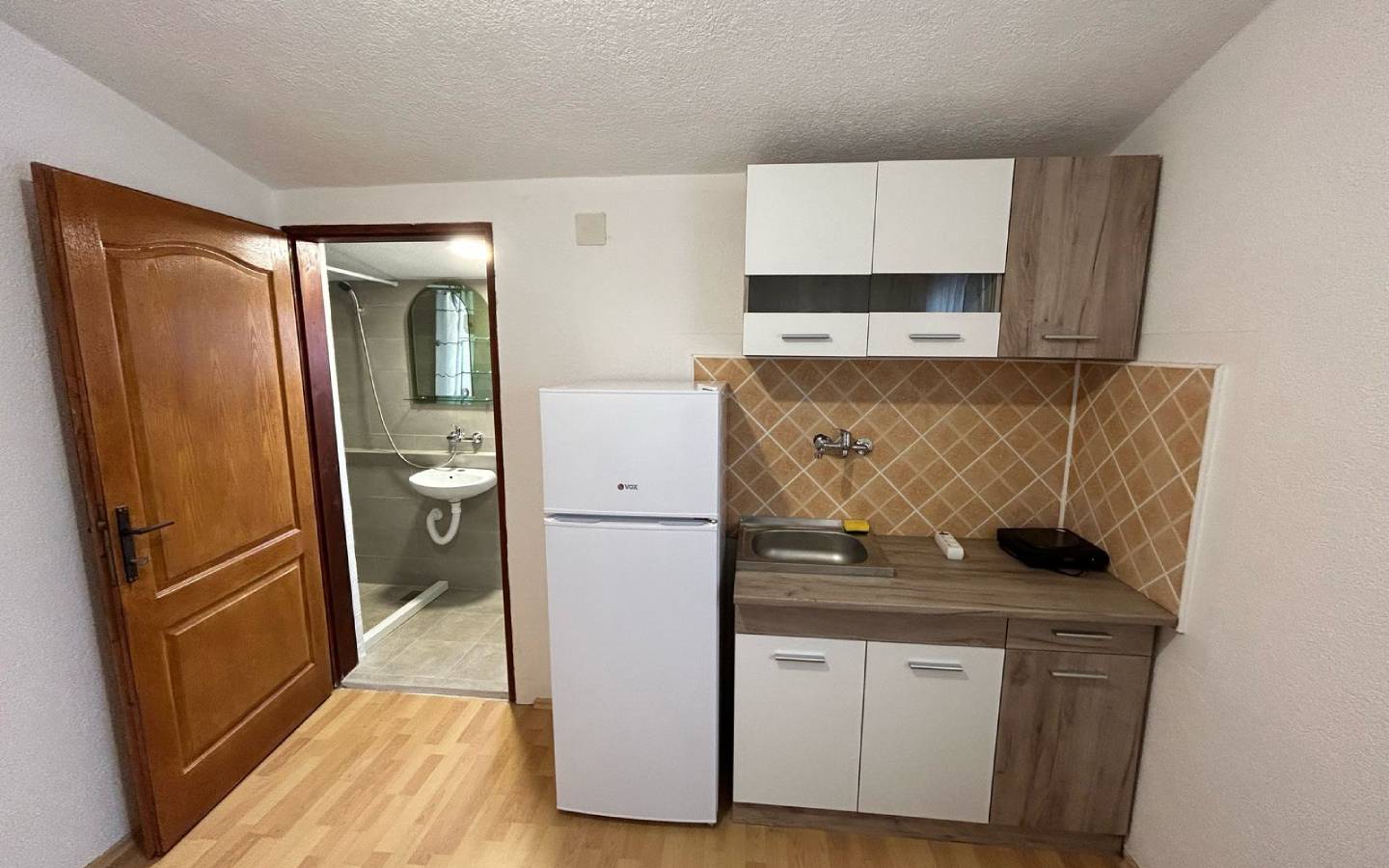 Modern compact kitchen in Ulcinj, Montenegro with appliances, stylish backsplash, and ensuite bath&mdash;exclusive at montenegro-listings.me by Ekosphere.