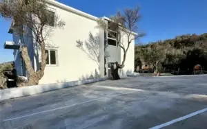 Modern white building with parking, lush greenery, and blue sky—prime Ulcinj real estate. Listed on montenegro-listings.me by ekosphere doo.
