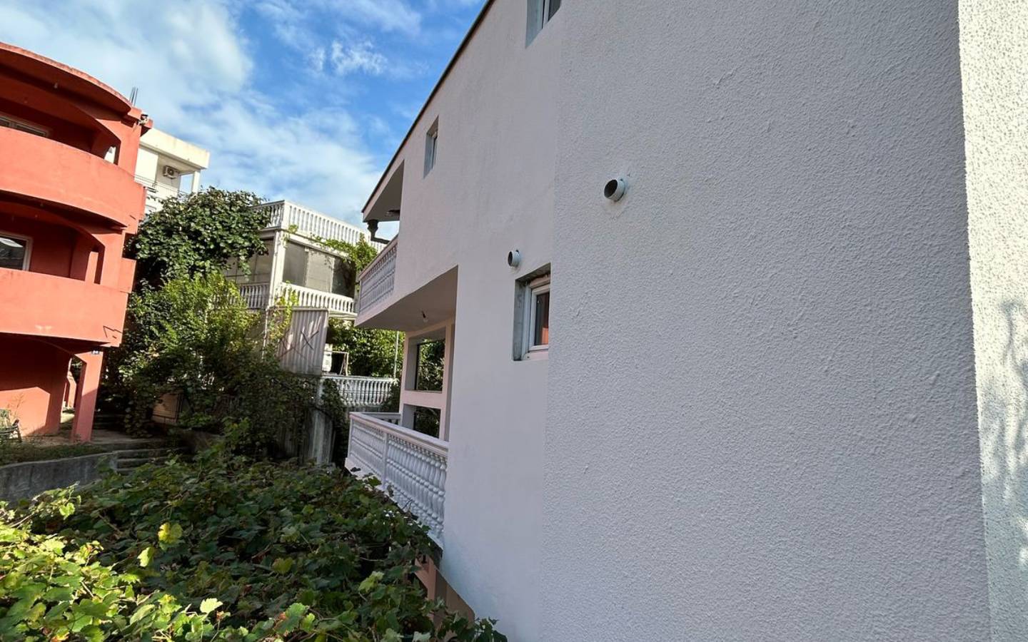 Modern white property in Ulcinj, Montenegro with balconies, security cameras, and lush greenery&mdash;exclusive on montenegro-listings.me by Ekosphere doo.