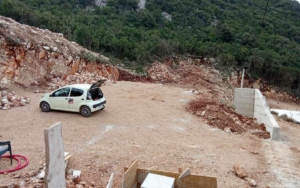 White car with open trunk parked on gravel site in Ulcinj, Montenegro—ideal for real estate investment. By ekosphere doo.
