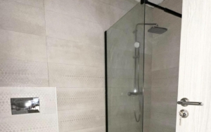Sleek Ulcinj bathroom with light tiles, glass shower, rainfall head—prime Montenegro real estate by ekosphere doo on montenegro-listings.me.