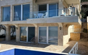 Contemporary two-story home in Ulcinj, Montenegro with glass doors, balcony, stone patio, pool—prime investment via montenegro-listings.me.