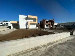 Modern white-beige home beside a red brick build in Ulcinj, Montenegro—prime real estate by ekosphere doo on montenegro-listings.me.