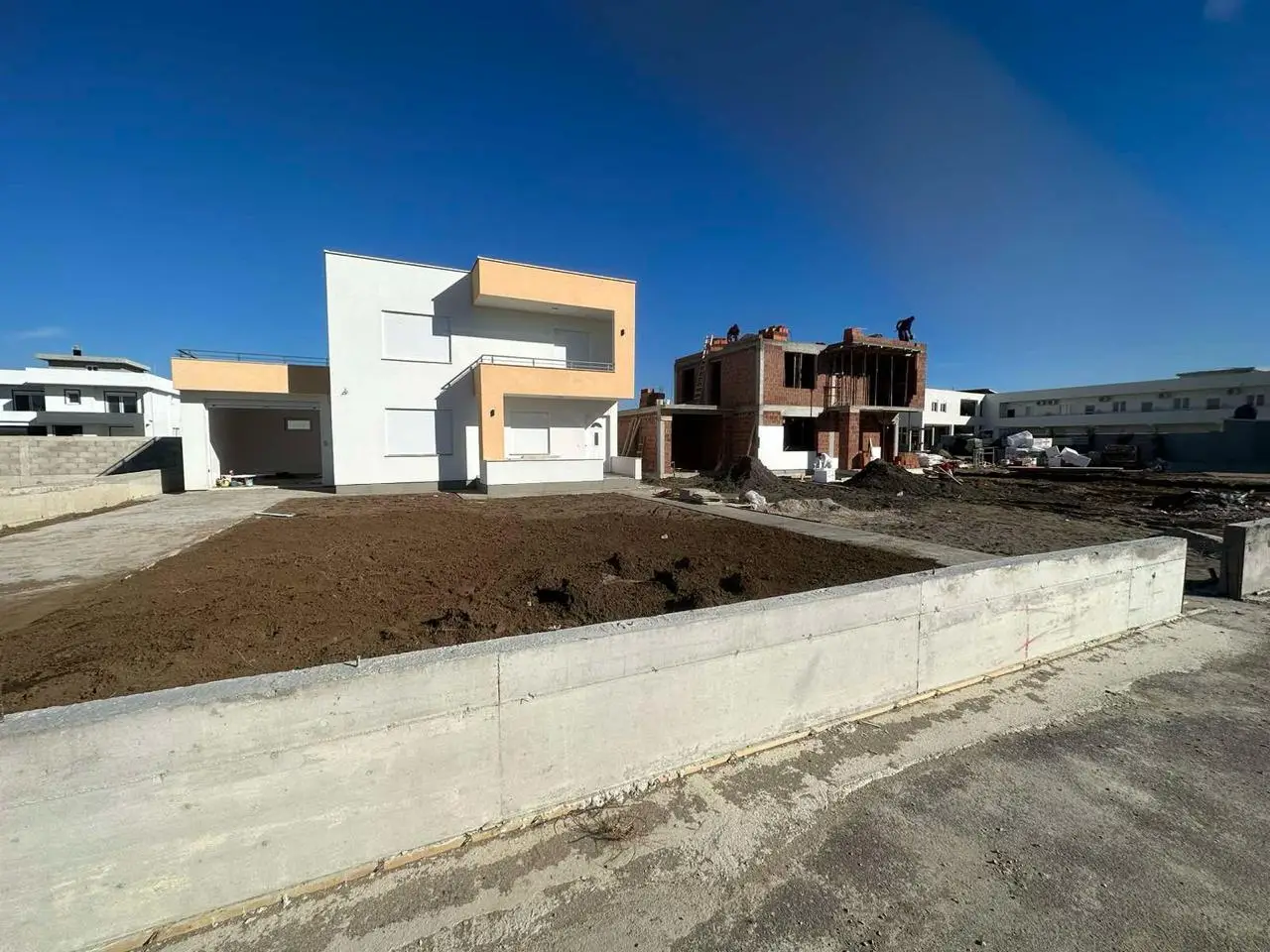 Modern white-beige home beside a red brick build in Ulcinj, Montenegro—prime real estate by ekosphere doo on montenegro-listings.me.