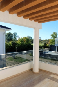 Experience luxury living in Ulcinj with this Adana Villa balcony—wooden slat ceiling, glass railings, and stunning views. Offered by montenegro-listings.me, a project of ekosphere doo.