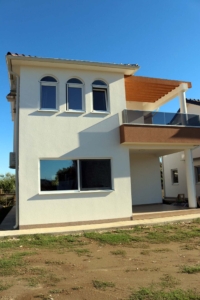 Stunning two-story Adana Villa in Ulcinj, Montenegro—white façade, arched windows, balcony, glass railings, exclusive at montenegro-listings.me by ekosphere doo.
