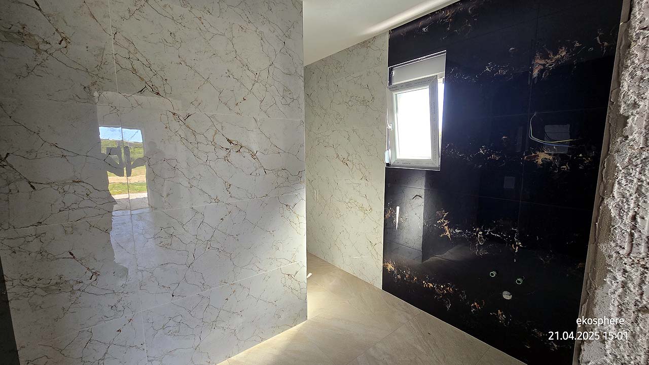 Modern bathroom in Ulcinj features marble tiles, black accent wall, natural light. Top Montenegro real estate by Ekosphere, on montenegro-listings.me.