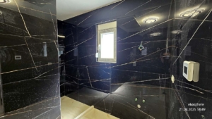 Modern Ulcinj bathroom with black marble walls, white fixtures, and natural light—exclusive at montenegro-listings.me by Ekosphere.