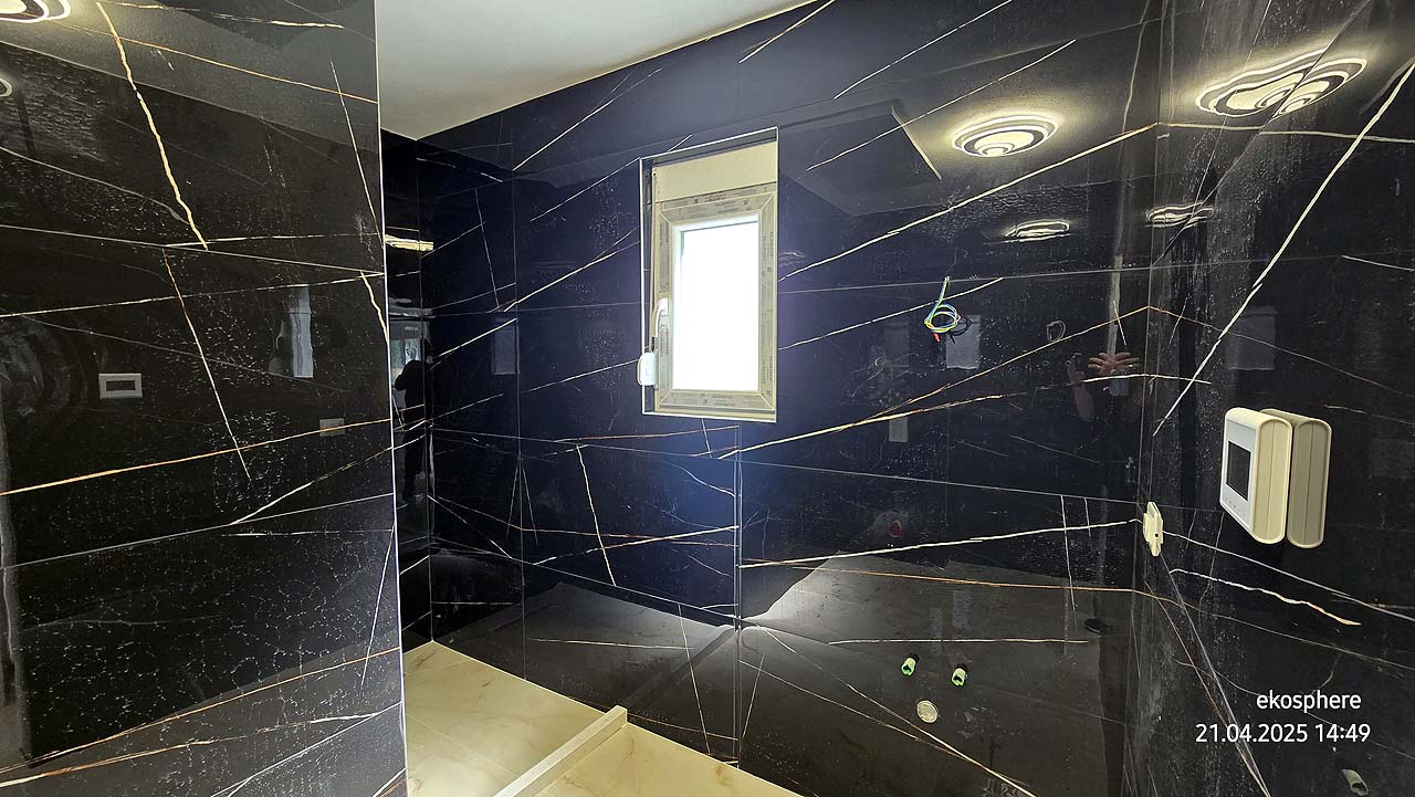 Modern Ulcinj bathroom with black marble walls, white fixtures, and natural light&mdash;exclusive at montenegro-listings.me by Ekosphere.