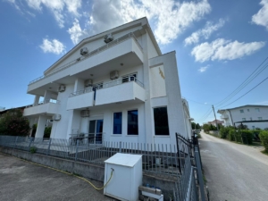 Modern white two-story home with balconies, fenced yard, and paved driveway in Ulcinj. Exclusive on montenegro-listings.me by Ekosphere doo.