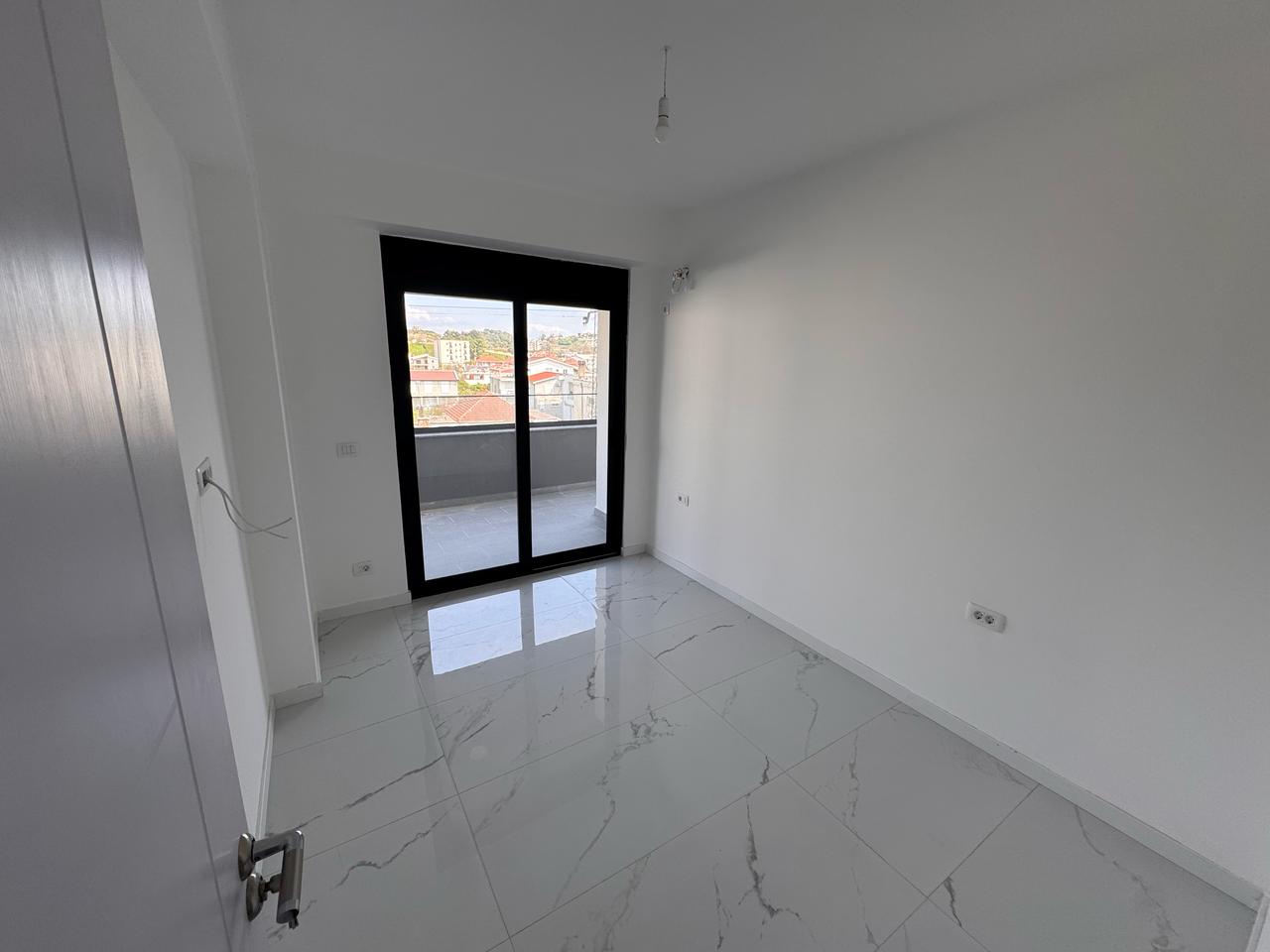 Bright, tiled room in prime Ulcinj real estate; large glass doors to balcony with city views. Exclusive on montenegro-listings.me by Ekosphere doo.