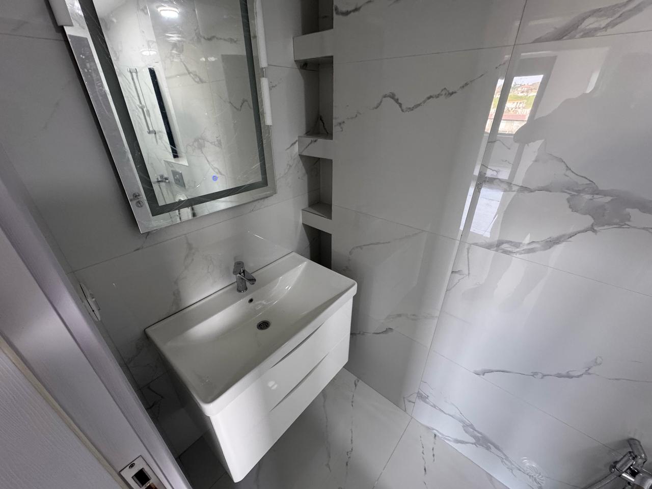 Luxury bathroom in Ulcinj: white marble, modern sink, built-ins, bright space. Invest with montenegro-listings.me by Ekosphere D.O.O.
