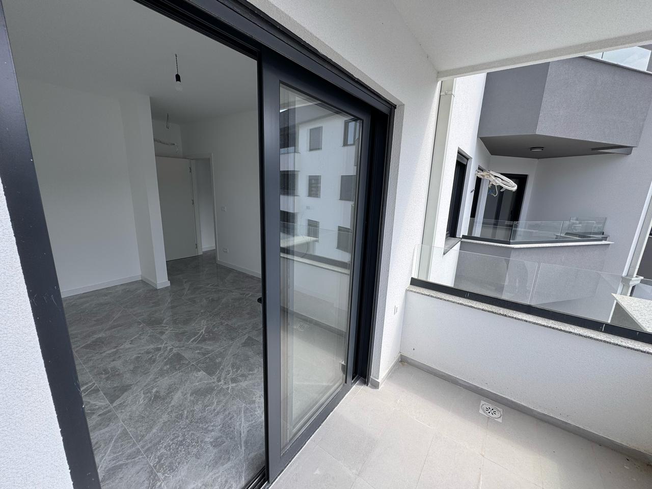 Modern covered balcony with light gray tiles; sliding doors open to airy, unfurnished interiors&mdash;prime Ulcinj real estate at montenegro-listings.me by ekosphere doo.