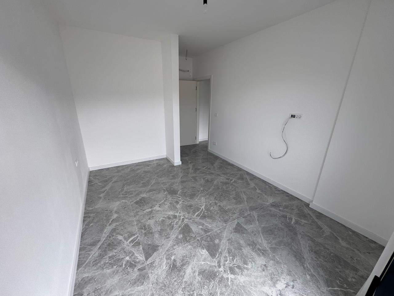 Spacious empty room in Ulcinj, Montenegro with white walls and gray tiled floor&mdash;prime investment from montenegro-listings.me by Ekosphere.