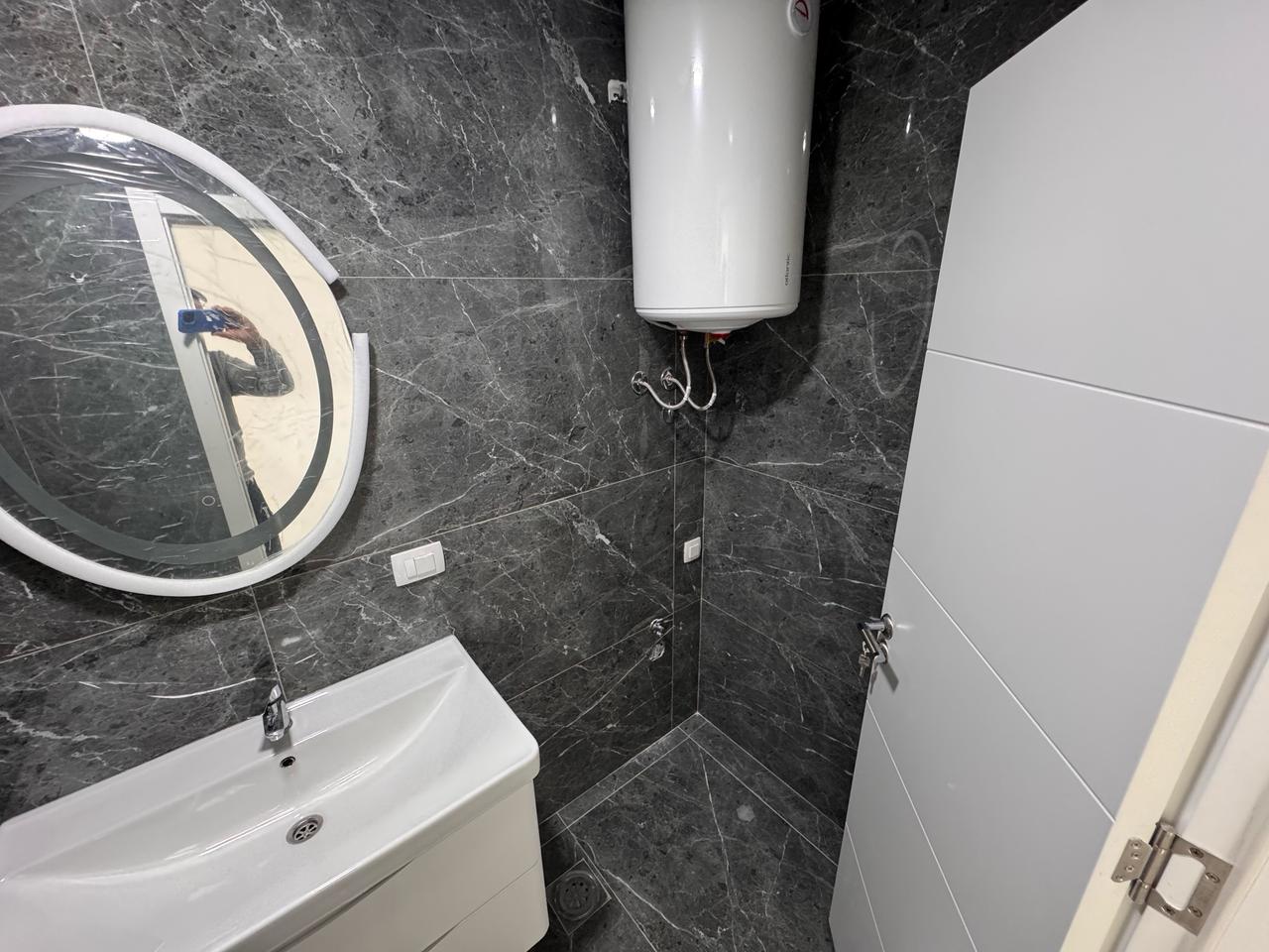 Modern bathroom in Ulcinj property with luxe dark marble, wall-mounted sink, quality fittings; exclusive via montenegro-listings.me/Ekosphere.