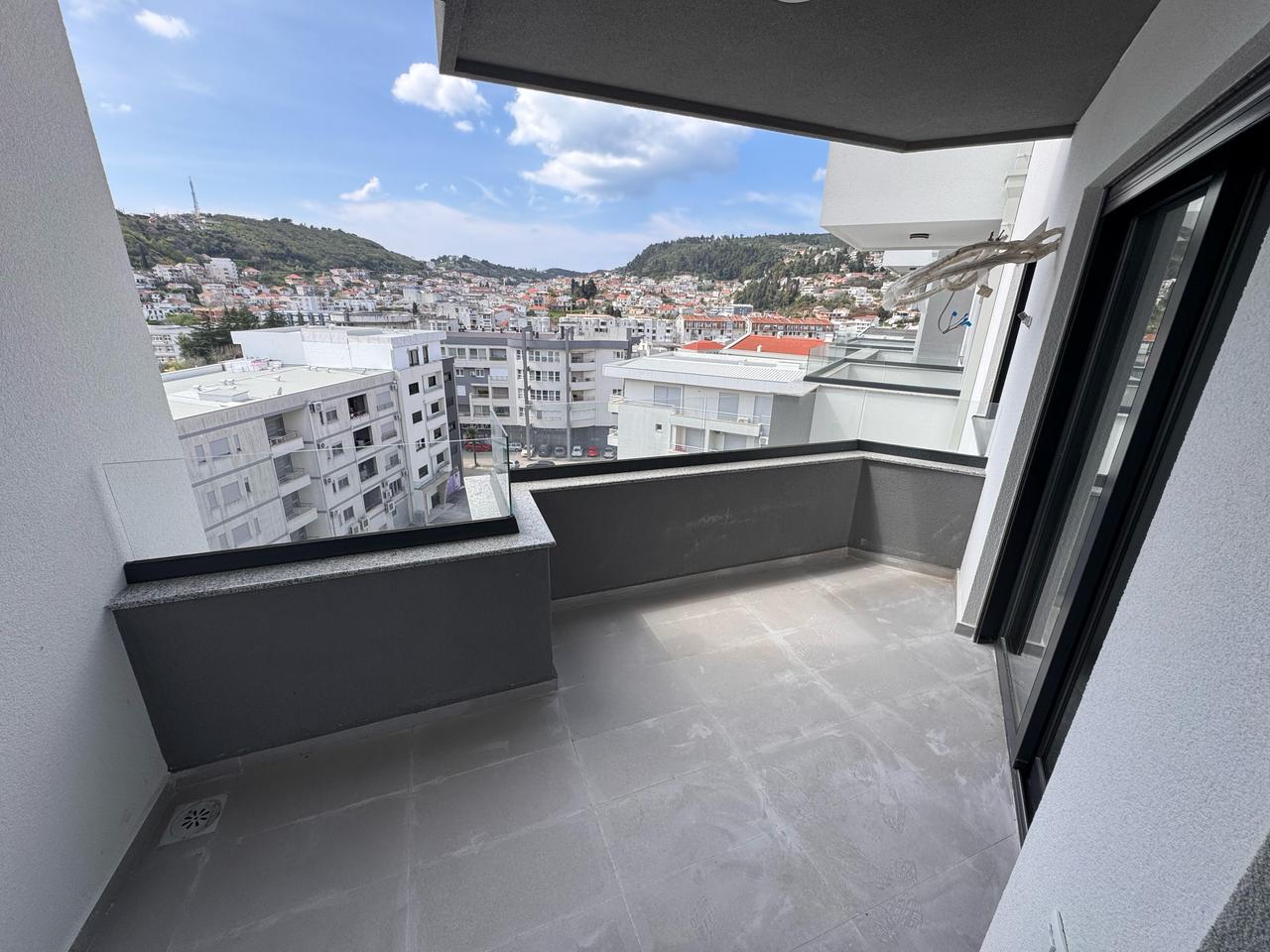 Luxury modern apartment balcony with tiled floors and glass railing, offering stunning Ulcinj city views&mdash;exclusive at montenegro-listings.me by Ekosphere doo.