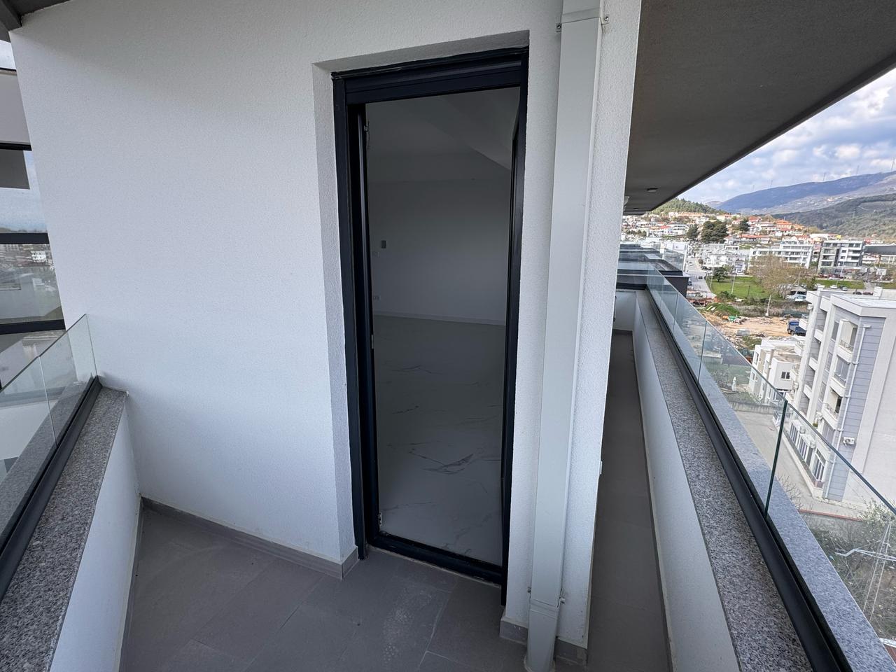 Spacious unfurnished Ulcinj apartment with glass balcony, cityscape views, green hills. Prime investment via montenegro-listings.me/Ekosphere DOO.