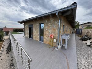 Elegant stone-clad home with spacious gray-tiled patio, glass doors, and modern railings—prime Ulcinj investment by ekosphere doo.