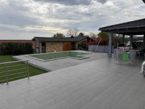 Spacious patio with gray tiles, empty rectangular pool, shed, green lawn—premium Ulcinj Montenegro property by ekosphere doo.