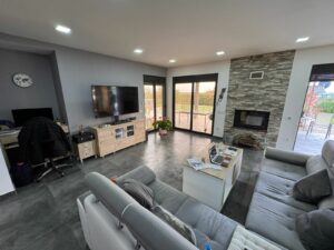 Stunning Ulcinj living room with gray sectional, fireplace, large windows—prime property for sale on montenegro-listings.me by Ekosphere.