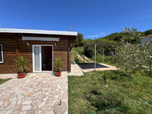 Charming wooden home with stone patio, carport, and lush lawn in Ulcinj. Invest via montenegro-listings.me by ekosphere doo.