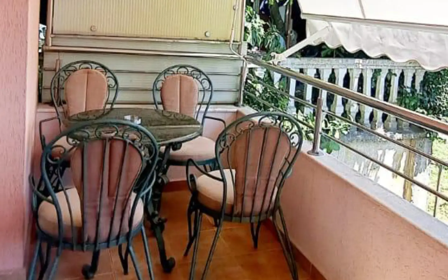 Elegant Ulcinj balcony with stone table, cushioned chairs, tiled floor, lush greenery&mdash;ideal property at montenegro-listings.me by ekosphere doo.