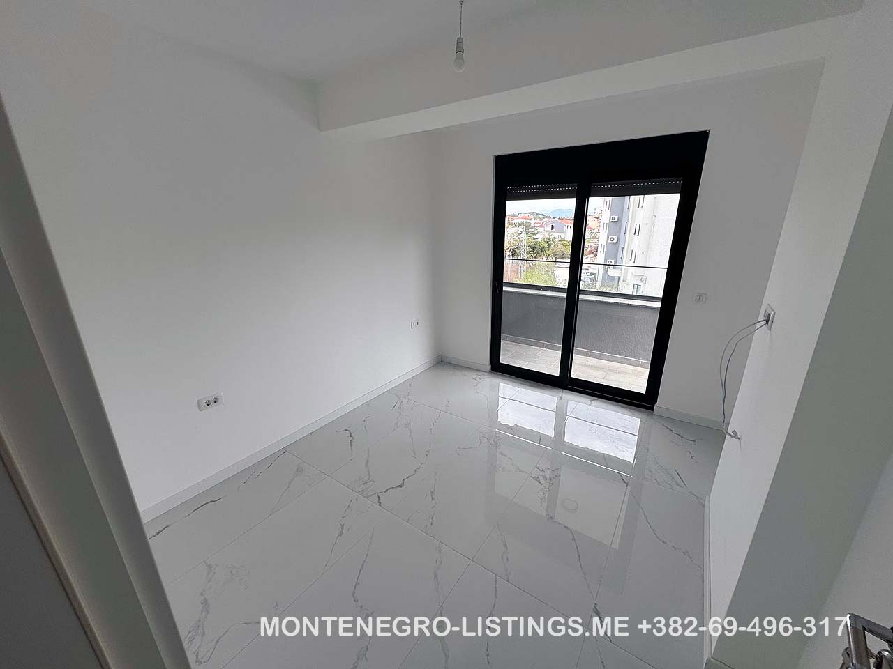 Modern, sunlit white room with marble tile floors, large windows, and balcony in Ulcinj. Montenegro-listings.me by Ekosphere doo.