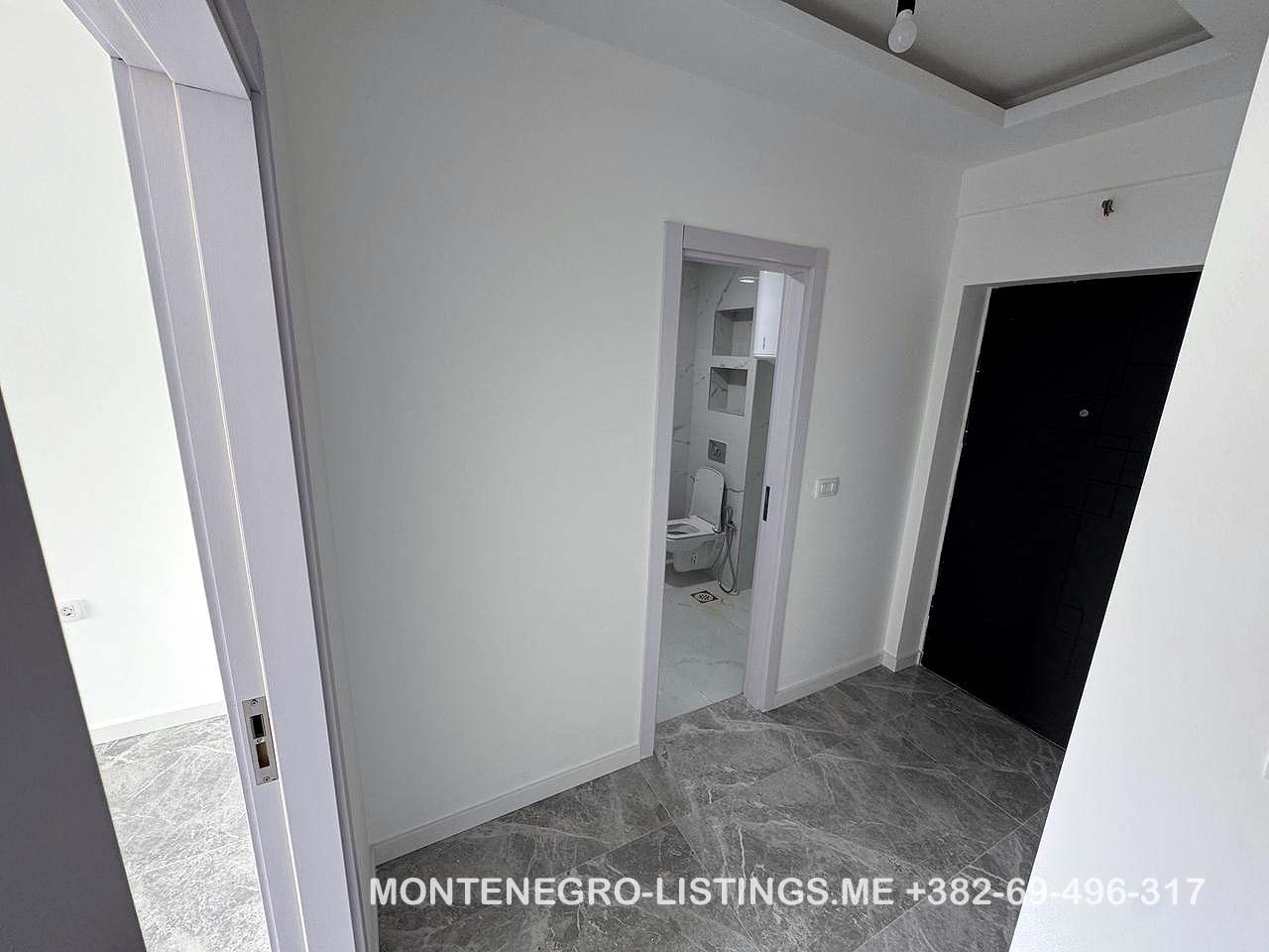 Modern hallway with gray tiled floors, white walls, 3 doors including a bathroom; prime Ulcinj real estate by montenegro-listings.me.
