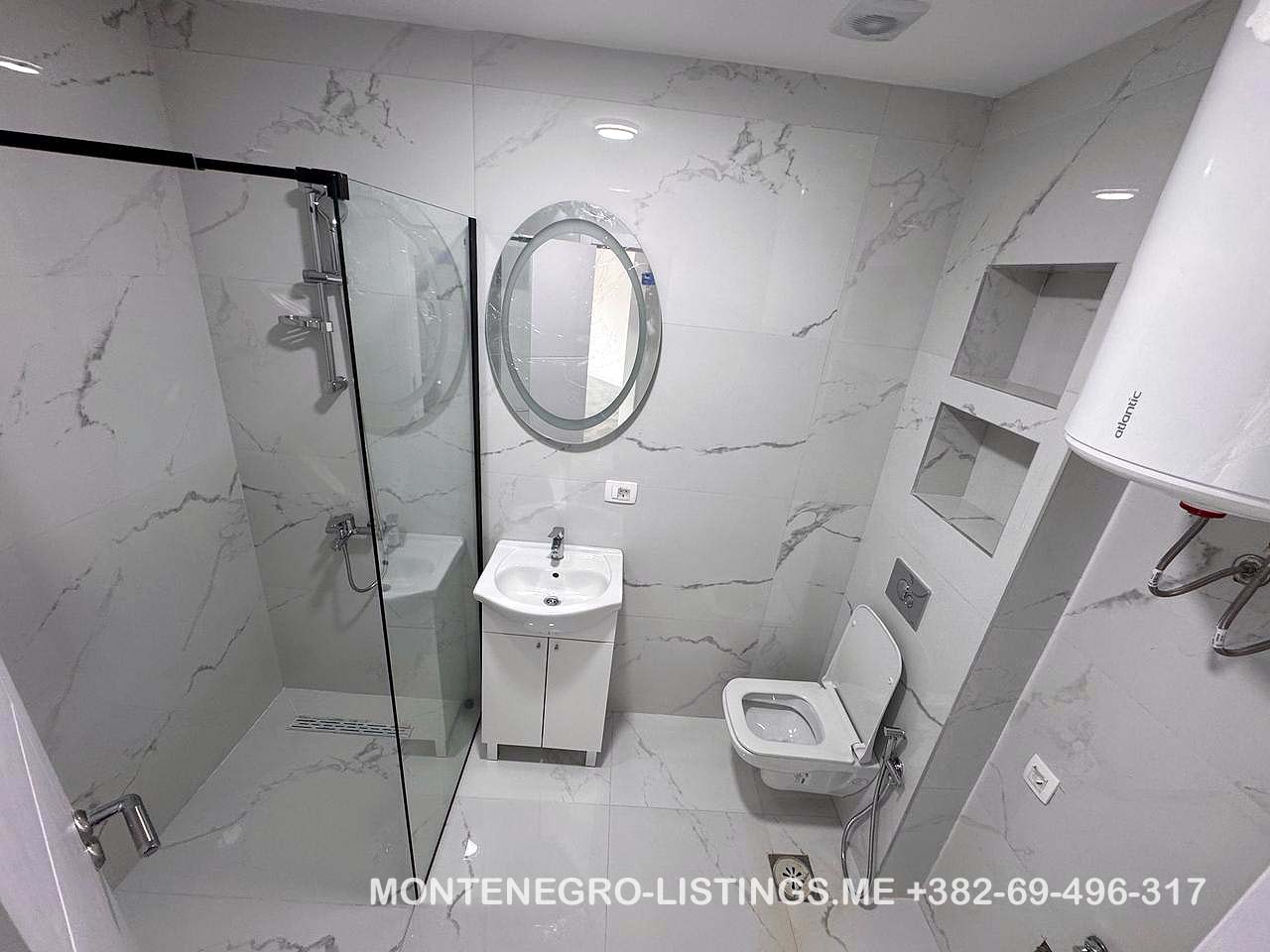 Elegant Ulcinj bathroom with marble tiles, glass shower, modern fixtures. Great real estate investment at montenegro-listings.me by Ekosphere.