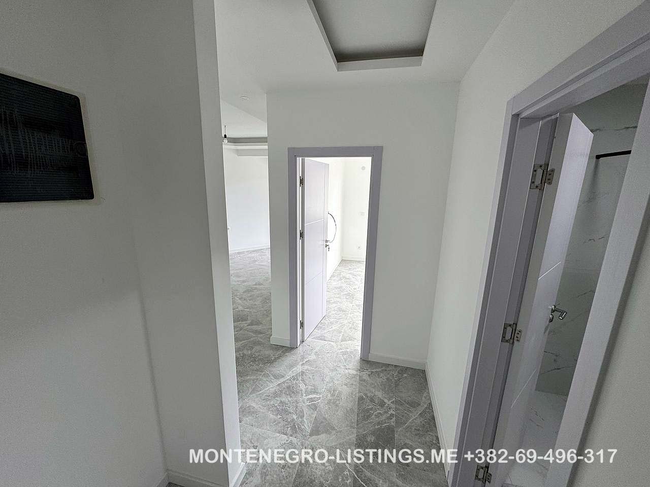Modern hallway with gray tiles, white walls, and three open doorways in Ulcinj&mdash;exclusive at montenegro-listings.me by ekosphere doo.