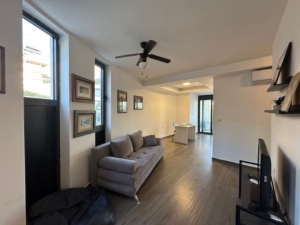 Elegant Ulcinj apartment: gray sofa, TV, wood floors, dining area & views—prime Montenegro real estate by Ekosphere on montenegro-listings.me.