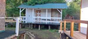 Charming white wooden cabin on stilts with green metal roof, porch, and parking in Ulcinj—prime real estate by montenegro-listings.me.