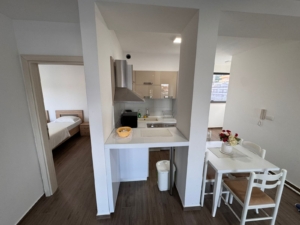 Modern kitchen with white cabinets, dining for four, leads to bedroom—ideal Ulcinj investment. Exclusively by montenegro-listings.me.