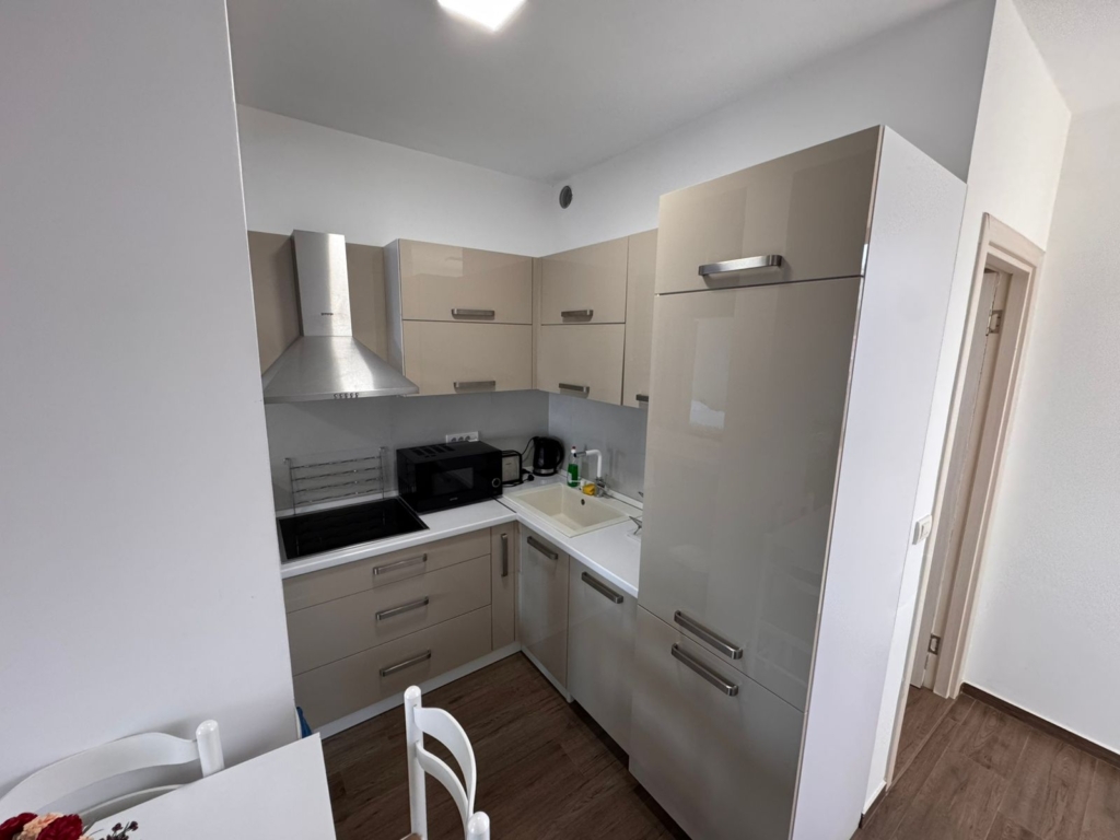Stylish compact kitchen in Ulcinj with beige cabinets, premium appliances, dining area—ideal Montenegro real estate by ekosphere doo.