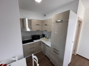 Stylish compact kitchen in Ulcinj with beige cabinets, premium appliances, dining area—ideal Montenegro real estate by ekosphere doo.