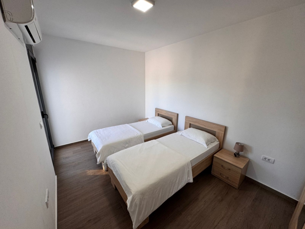 Modern Ulcinj bedroom: two single beds, white bedding, AC, wood floors—prime Montenegro real estate via montenegro-listings.me/Ekosphere.