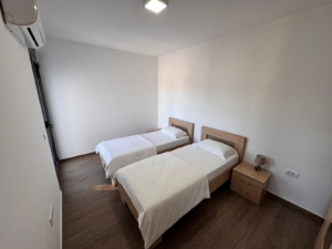 Modern Ulcinj bedroom: two single beds, white bedding, AC, wood floors—prime Montenegro real estate via montenegro-listings.me/Ekosphere.