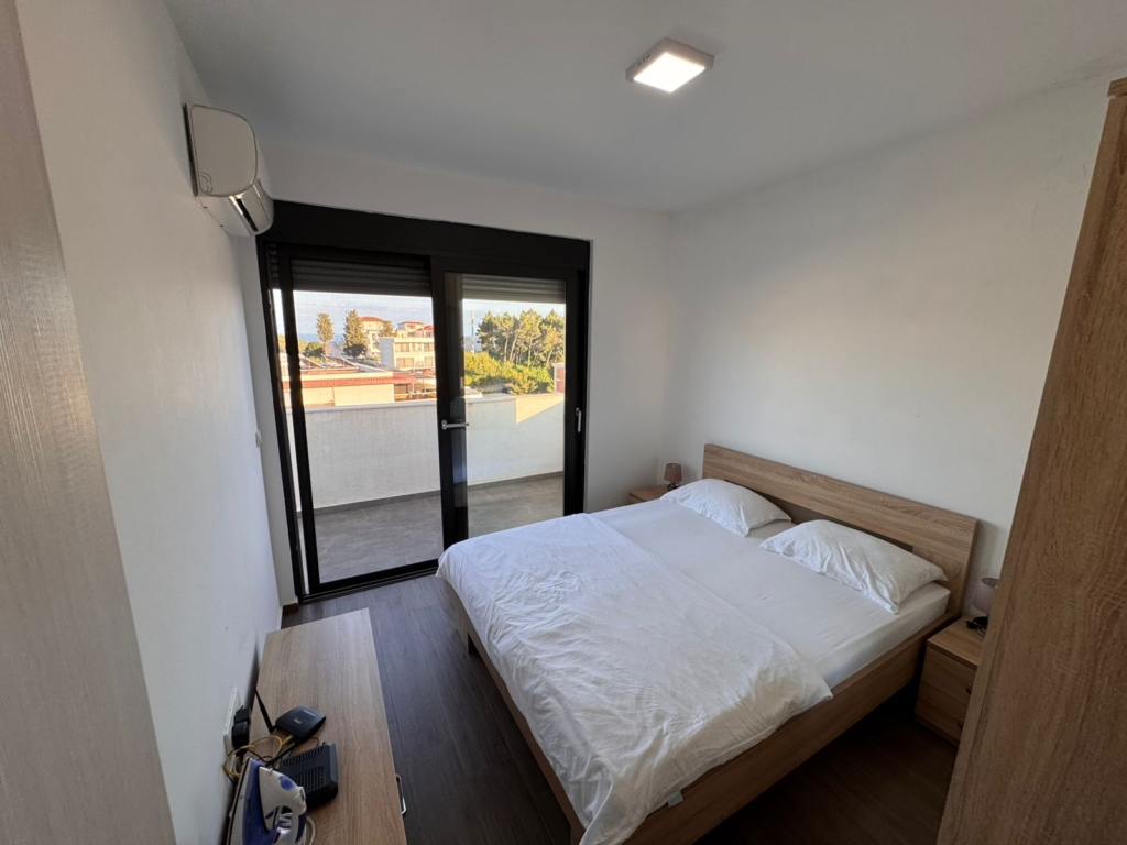 Luxurious Ulcinj Montenegro bedroom with double bed, AC, elegant wood décor & balcony views—exclusive on montenegro-listings.me by ekosphere doo.